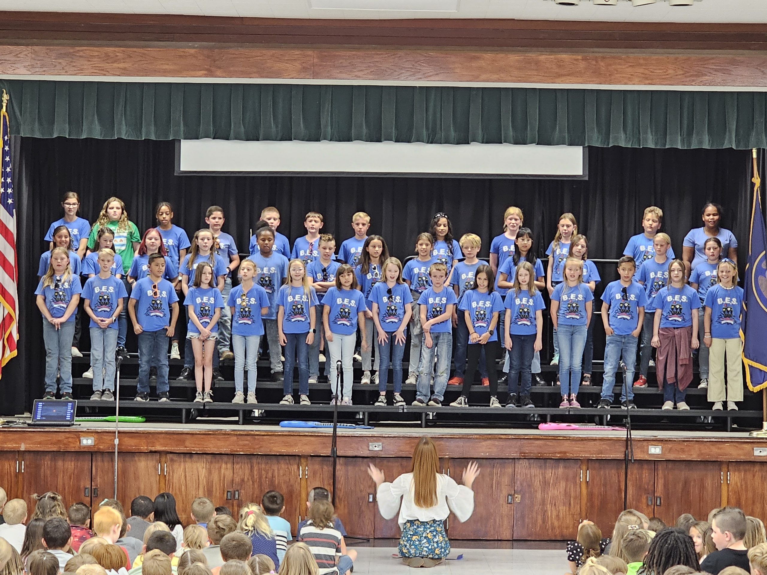 Choir performance on the stage with their choir shirts on. 